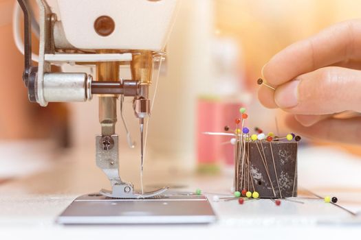 Close up of female hand holding a needle in a tailor workshop