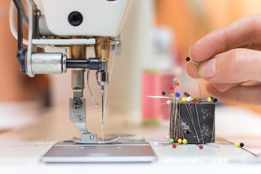 Close up of female hand holding a needle in a tailor workshop