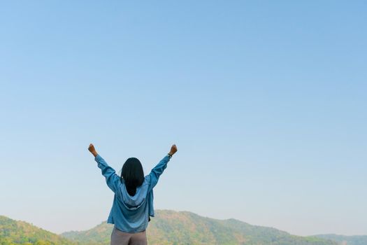 Woman rise hands up to sky freedom concept with blue sky and summer field mountain background.