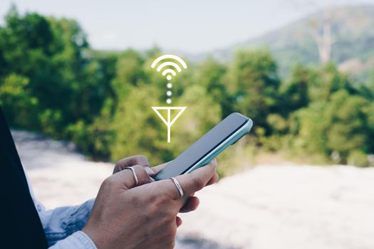 People hand using smartphone looking for signal wifi in off the grid no power space area or in the wood jungle.