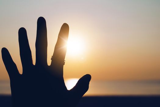 Hand reach out to sunset sky beach sand nature background. Relax and rest in vacation time.