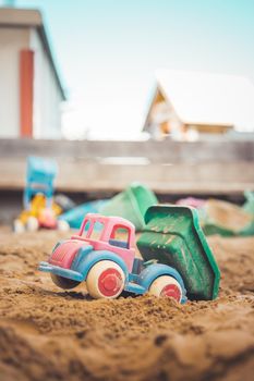 Children plastic toys in the sand box. Truck, selective focus.