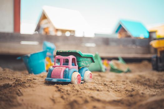 Children plastic toys in the sand box. Truck, selective focus.