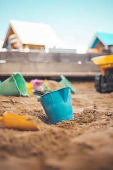 Children plastic toys in the sand box. Dirt bucket, selective focus.