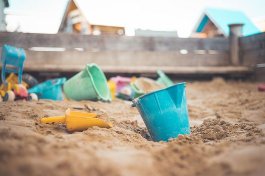 Children plastic toys in the sand box. Dirt bucket, selective focus.