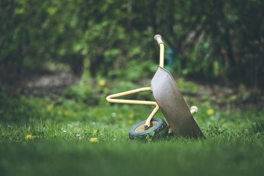Tipped child hand barrow in green garden