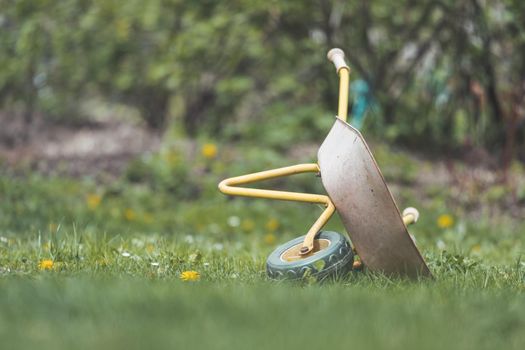 Tipped child hand barrow in green garden