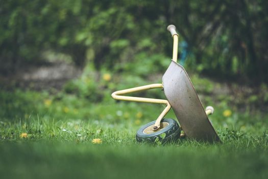 Tipped child hand barrow in green garden