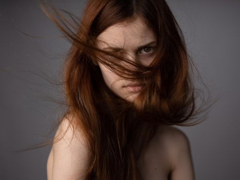 face of a red-haired woman on a gray background bare shoulders close-up model. High quality photo