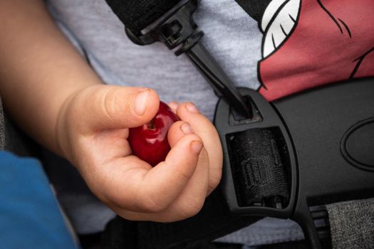 Closeup of a little cute baby hand holding a red cherry - childhood