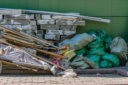 Construction waste dump in the shade behind a building under construction