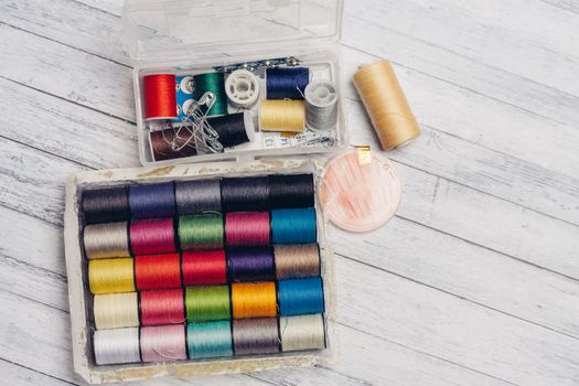 ball of multicolored threads in a box and sewing supplies needles and pins on a wooden table. High quality photo