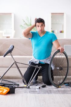Young man repairing bicycle at home