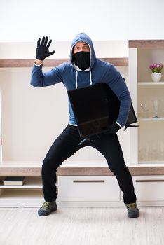 Man burglar stealing tv set from house