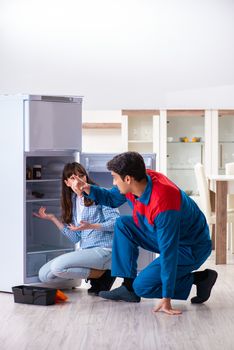 Man repairing fridge with customer