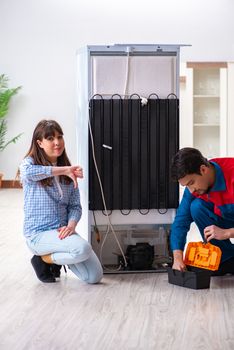 Man repairing fridge with customer