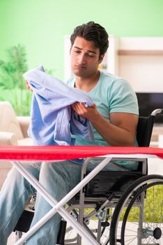 Disabled man on wheelchair ironing clothing