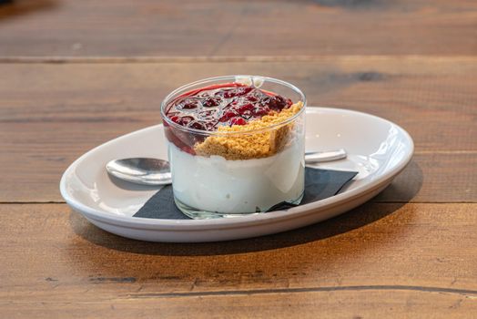 Cheesecake served in a glass with a berry sauce.