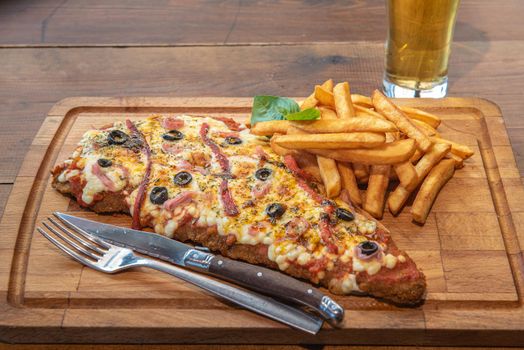 Typical Neapolitan Milanese typical food from Argentina and Uruguay served with French fries and on wooden board.