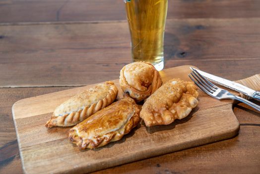 Varied Argentine empanadas with different fillings on a wooden board.