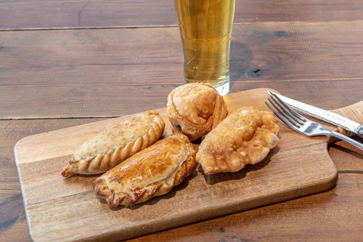 Varied Argentine empanadas with different fillings on a wooden board.