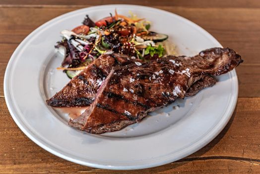 Argentine cut of meat called Entrana with vegetables and served on a white plate.