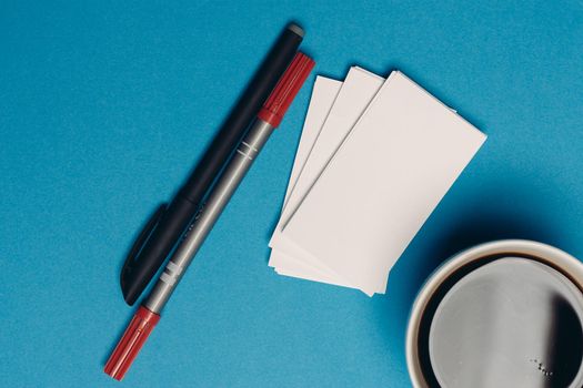 business cards on blue background and pen coffee cup top view. High quality photo