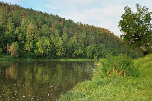 Colorful landscape with mountains and a beautiful calm river in Russia. River Ay. Summer, river rafting