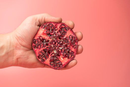 a hand squeezing juice from a pomegranate into a glass. High quality photo
