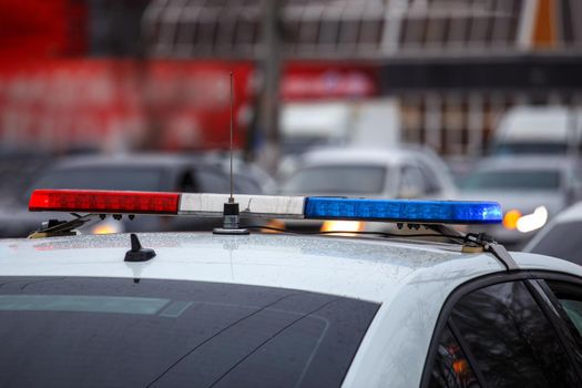 police car lights in city street at winter day with cars traffic in blurry background.