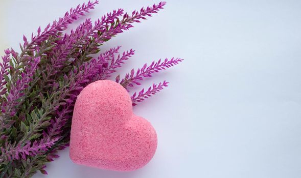 Purple heart bath salt and a branch of artificial lavender on a white background. Space for text.