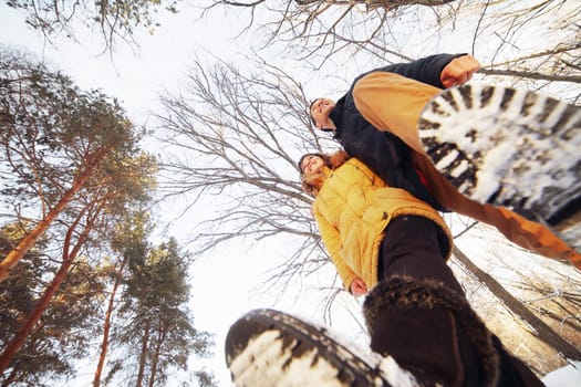 Cheerful young couple walking in the winter forest, low angle.