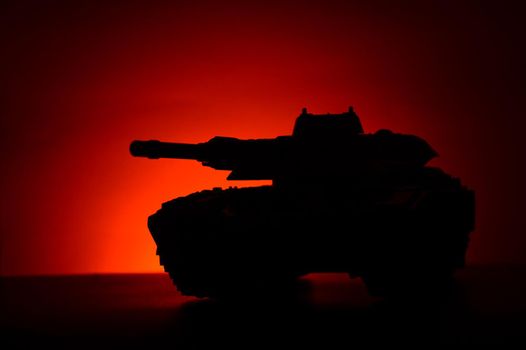 A military tank silhouette over a sunset background with deep red and orange hues which add atmospheric mood.