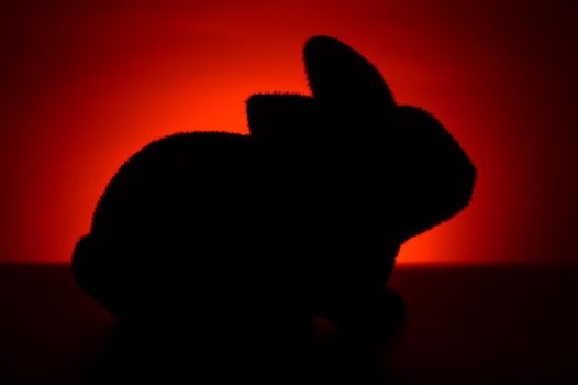 A silhouette of a furry bunny rabbit during the red and orange hues of the sunrise.
