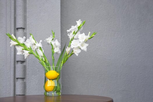 Fresh plants in organic cafe table flowers vase with lemons in vegan restaurant. Concept summer flowers setting decoration fresh interior with concrete wall cafe design elements of organic restaurant