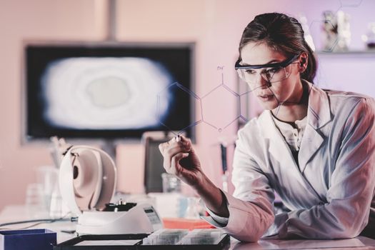 Portrait of a confident female health care expert in life science laboratory writing structural chemical formula on a glass board. Healthcare and modern life science concept. Blue toned image.