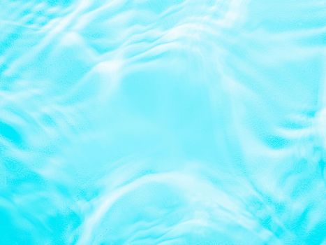 Ripple water texture on blue pool background. Shadow of water on sunlight. Mockup for product, spa or travel background. Marble blue water surface as wallpaper background