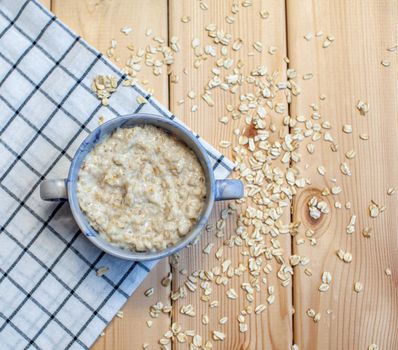 Fresh oatmeal porridge in a plate on a beautiful napkin and on a wooden table. A fresh and healthy breakfast.