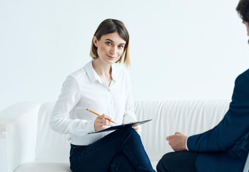 A woman with documents listens to the problems of a man on a light background psychologist. High quality photo