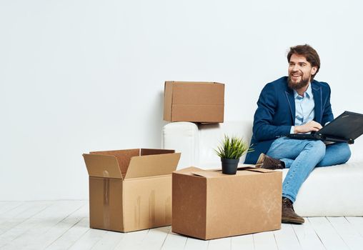 Business man sitting on the couch with laptop boxes with things unpacking office official. High quality photo