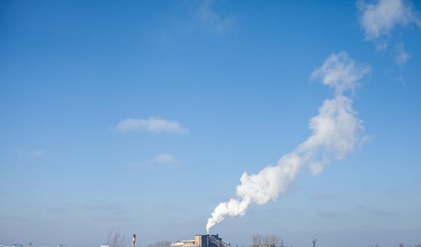 White thick smoke from the boiler room chimney. Smoke against the blue sky. Air pollution. Heating of the city. Industrial zone.