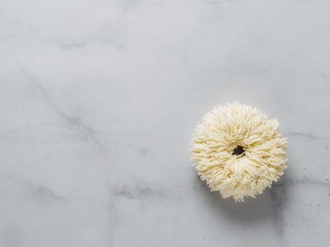 Shag donut on white marble background. Unusual trendy donut with white vanilla buttercream. Copy space. Top view or flat lay.