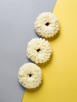 Shag donuts on two color gray and yellow background. Unusual trendy donuts with white vanilla buttercream. Copy space. Top view or flat lay. Vertical