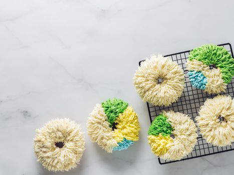 Shag donuts on white marble background. Unusual trendy colorful donuts with vanilla buttercream. Copy space. Top view or flat lay.