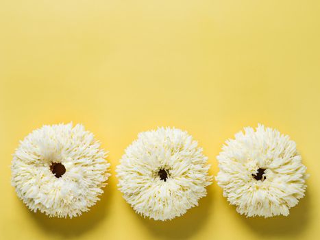 Shag donuts on bright yellow background. Unusual trendy donuts with vanilla buttercream. Copy space. Top view or flat lay.