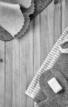 Accessories for visiting the bath or sauna on a wooden background: towel, bath mat, felt hat, washcloth, soap. Top view with copy space. Flat lay