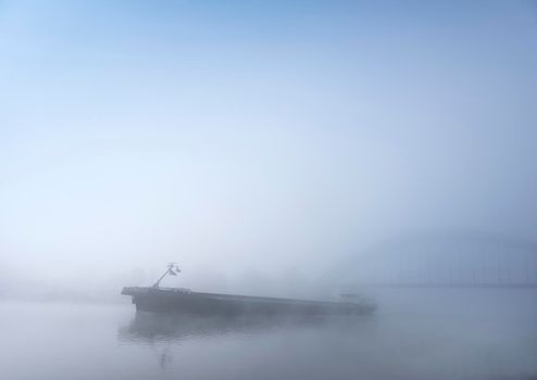 barge and bridge in the fog on river rhine near utrecht in the netherlands