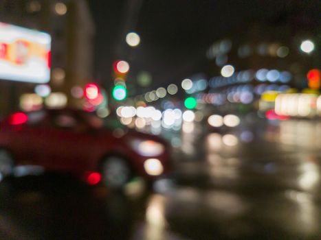 defocused night rain city street cross roads view with red car.