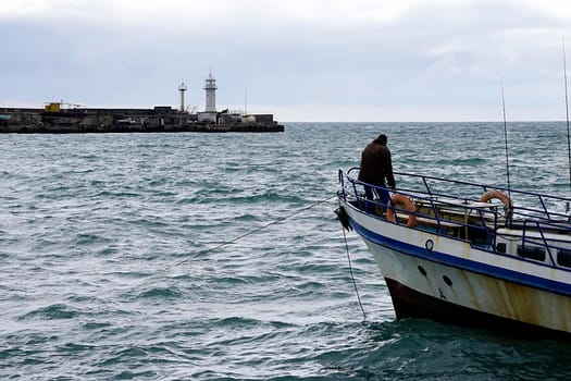 Seascape with a view of the fisherman on the bow of the ship. Yalta, Crimea