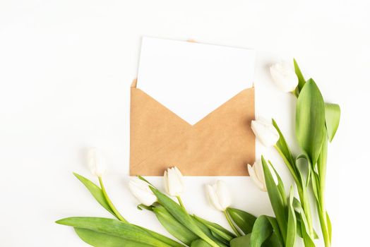 Mock up design. Fresh cut white tulip flowers and blank card with envelope top view on white background with copy space